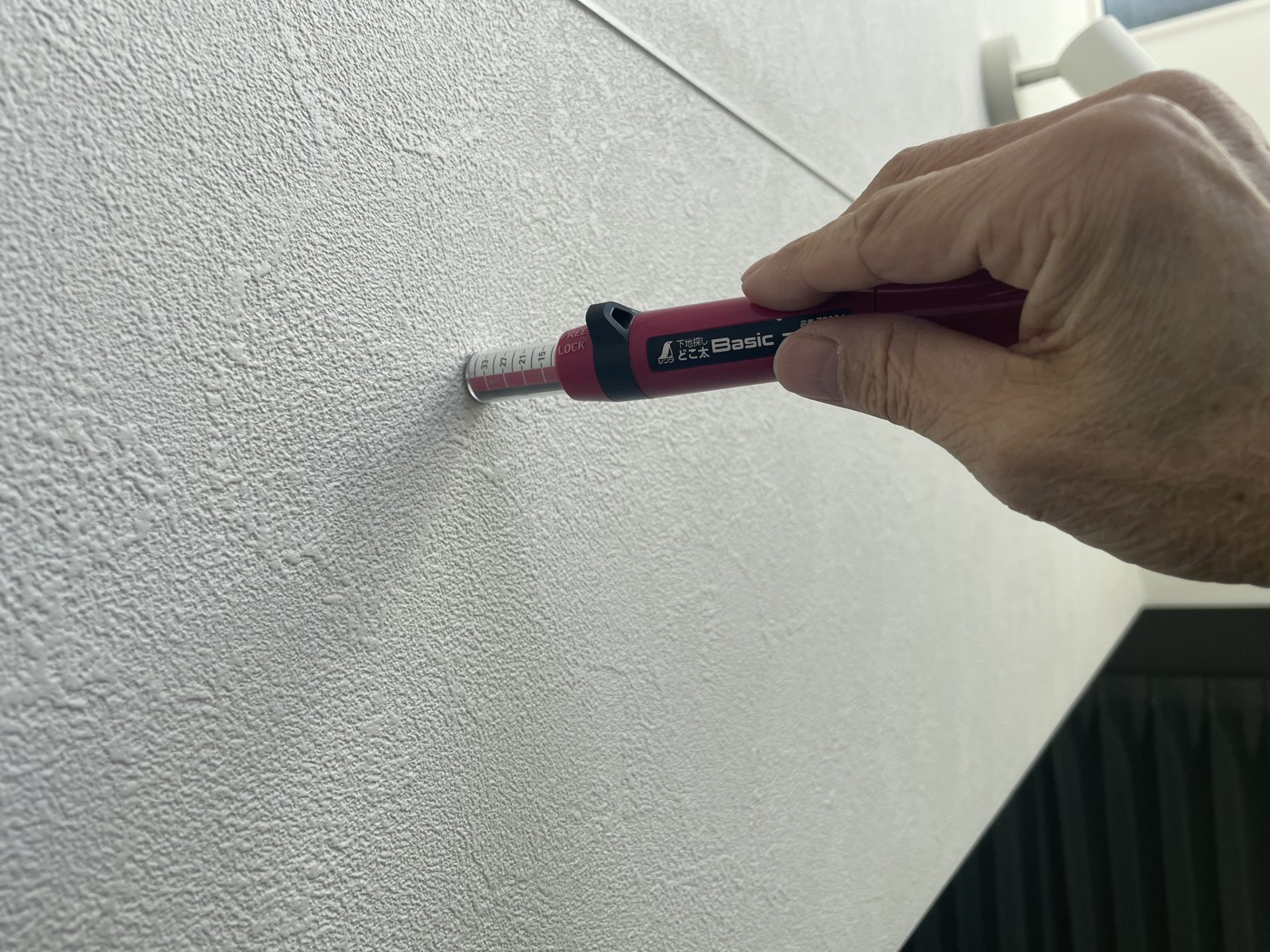 吹き抜け天幕設置前の下地調査。センサーと針式の2つの道具を使って木下地の位置を確認中