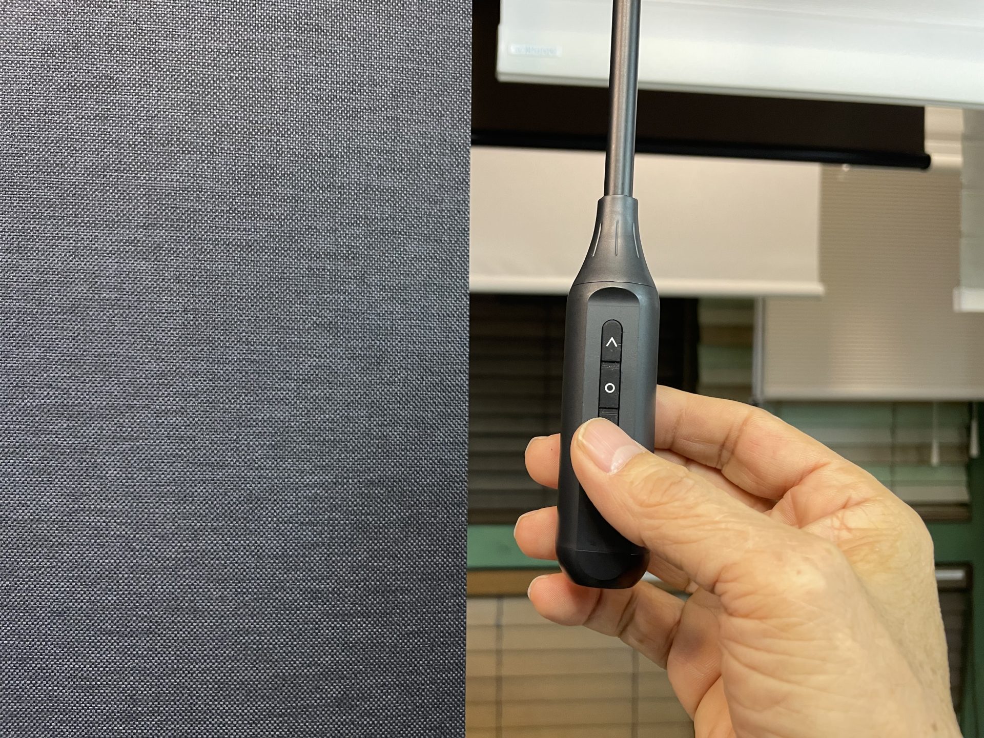 Eスティック電動ロールスクリーンの操作部アップ。上げる・下げる・止まるの3ボタンで簡単操作。